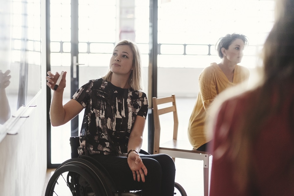 Person in wheelchair writing on a whiteboard