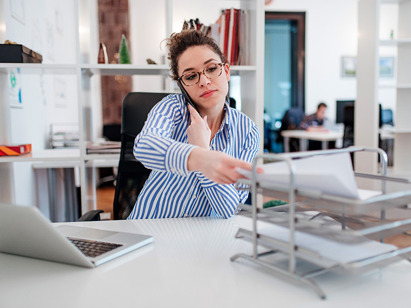 A photo of Shona who is answering the phone and putting a paper in a filing tray
